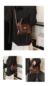 Detail view of a vintage dark brown leather shoulder bag with gold hardware and silk scarf