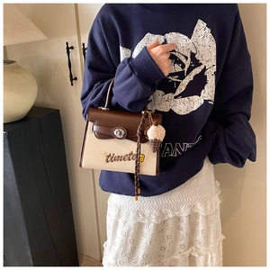 Detail of canvas leather patchwork bag with embroidery, lock closure and plush pendant