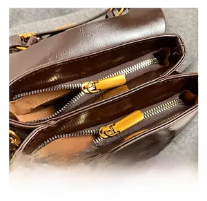 Detail of brown leather bag with double zippers and shiny gold metal hardware