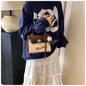 Detail of canvas shoulder bag with brown leather trim, timeto embroidery and ice cream charm
