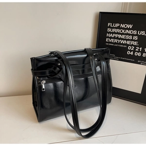 Detail of minimalist black faux leather tote with silver zipper and double shoulder straps