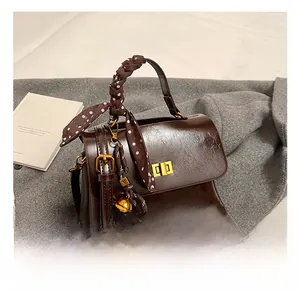 Detail of dark brown vintage handbag with gold clasp, scarf-wrapped handle and charms
