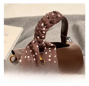 Detail of dark brown leather handbag handle wrapped in polka dot silk scarf with gold hardware