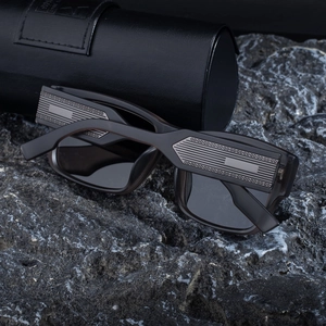 Macro detail of silver metal 4G logo on black square sunglasses with leather case