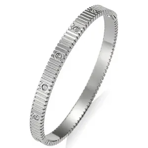 Détail macro d'un bracelet jonc en acier inoxydable argenté avec gravures et zircons