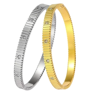 Interlocking gold and silver stainless steel bangles with ribbed texture and set stones