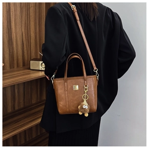 Detail of vintage brown crossbody bucket bag with gold plaque and plush monster charm