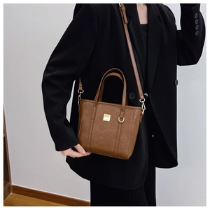 Close-up of brown faux leather tote bag featuring gold hardware and adjustable strap