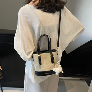 Sac seau bicolore rétro beige et noir avec breloque en peluche et finitions dorées
