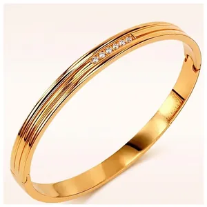 Elegant gold stainless steel bangle with five inset sparkling crystals on cream background