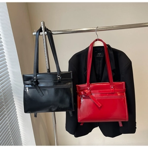 Detail of glossy patent leather tote bags with bow knot and practical front zipper pocket