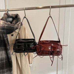 Retro glossy leather underarm bags in black and burgundy with bow tassels on a hanger