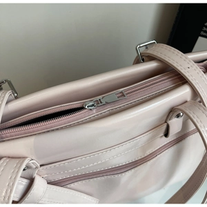 Detail view of smooth pink PU tote bag featuring a silver metal zipper and outer pocket