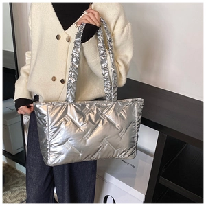 Detail of silver quilted tote bag featuring a ruffly pleated handle and metallic finish