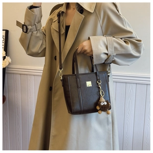 Detail view of a vintage dark coffee tote bag with luxury gold buckle and plush charm