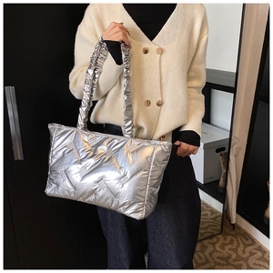 Silver quilted tote bag with metallic finish and ruffled handle shown on model
