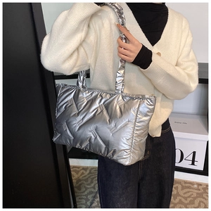 Close-up of metallic silver quilted puffer bag showing V-shaped stitching and shiny texture