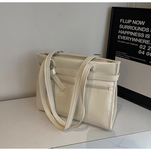 Detail of minimalist cream-white PU leather tote bag with functional zippers and buckles
