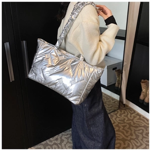 Detail of silver quilted puffer tote bag with metallic texture and ruched shoulder strap