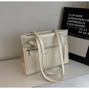 Detail of white glossy PU leather tote bag featuring belt straps and front zipper pocket