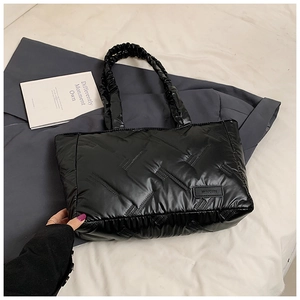 Detailed view of black quilted tote bag with diamond pattern and brand leather tag