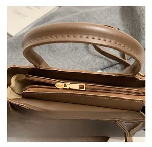 Gros plan du sac en cuir marron avec fermeture éclair dorée et coutures détaillées sur laine
