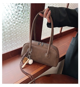 Detail of brown litchi grain leather bowling bag with vintage baseball charm