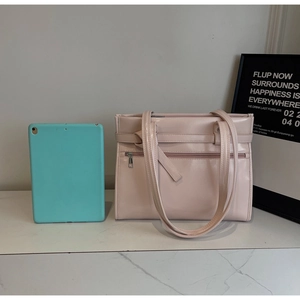 Close-up of pink leather tote bag with decorative strap and functional front zipper