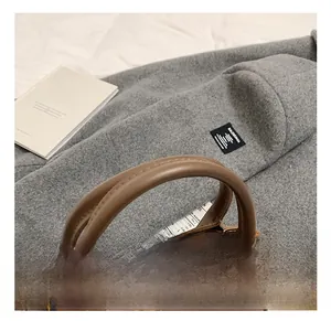 Gros plan d'un sac seau en cuir marron avec double poignée arc et fermeture éclair dorée
