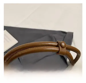 Détail du sac en peluche marron montrant la poignée en cuir et les coutures fines