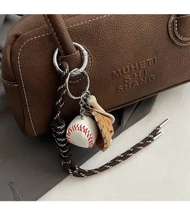 Detailed close-up of a baseball-themed keychain charm on a textured brown leather bag