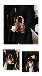 Détail du sac bandoulière en daim café avec anses roses et breloque ours en peluche