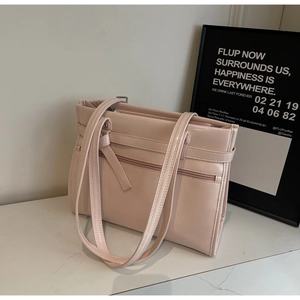 Detail shot of a beige patent leather tote bag with decorative straps on marble surface