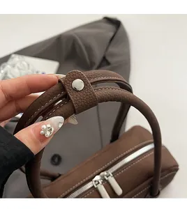 Close-up of premium brown leather texture with silver dual metal zippers on baguette bag