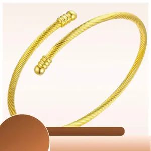 Elegant gold twisted cable open bangle featuring spherical end caps on white background