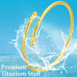 Minimalist twisted gold titanium steel rope cuff bracelet with spherical ends in water spray