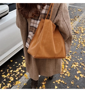 Detailansicht der karamellbraunen Krokodil-Prägung auf der Shopper-Tasche im Herbst