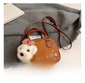 Détail d'un sac en daim marron avec broderie de cœur et charmant pendentif chien blanc