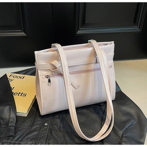 Close-up of pink faux leather handbag featuring silver zipper pockets and decorative straps