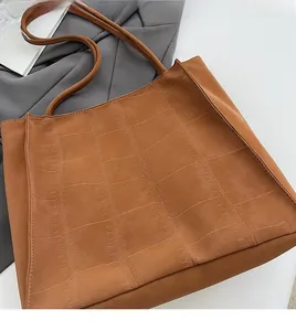 Detail einer braunen Tragetasche mit hochwertiger Krokodilhaut-Prägung aus Veloursleder