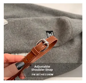 Gros plan sur la bandoulière en cuir marron réglable avec boucle argentée et surpiqûres