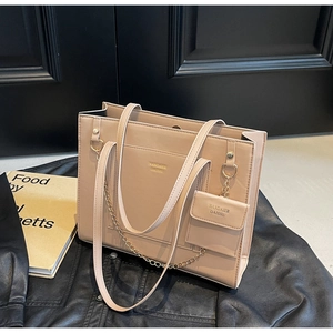 Detail of beige tote bag with gold chain and matching coin purse on leather jacket