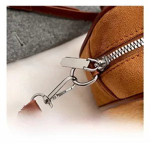 Détail du fermoir mousqueton argenté et du zip sur le sac bandoulière en daim marron