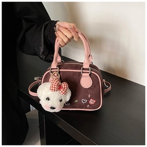 Détail du sac bowling rétro en daim marron avec anses roses et charm chien en peluche