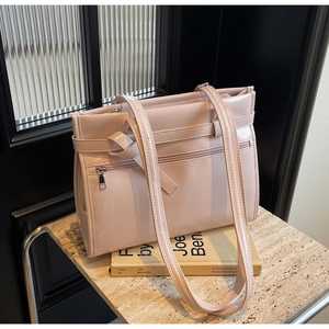 Close-up of a pink patent leather tote bag with glossy finish and decorative zippers