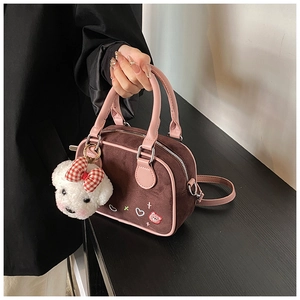Détail d'un sac bandoulière en daim marron avec garniture rose et breloque ours en peluche