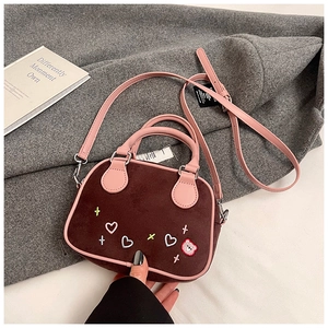 Détail du sac bandoulière en daim avec écusson ours et broderie sur manteau gris