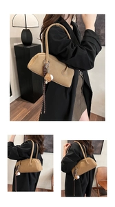 Detail of camel leather baguette bag with white contrast stitching and baseball charm
