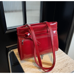 Detail of red glossy tote bag with multiple zipper pockets and sleek metal hardware