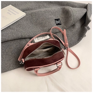 Détail du sac en daim bordeaux avec bandoulières en cuir rose et compartiments internes